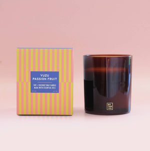 Candle and its packaging with a pink background
