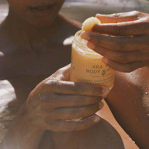 Person holding a jar of Sea Salt Body Scrub with a blurred background