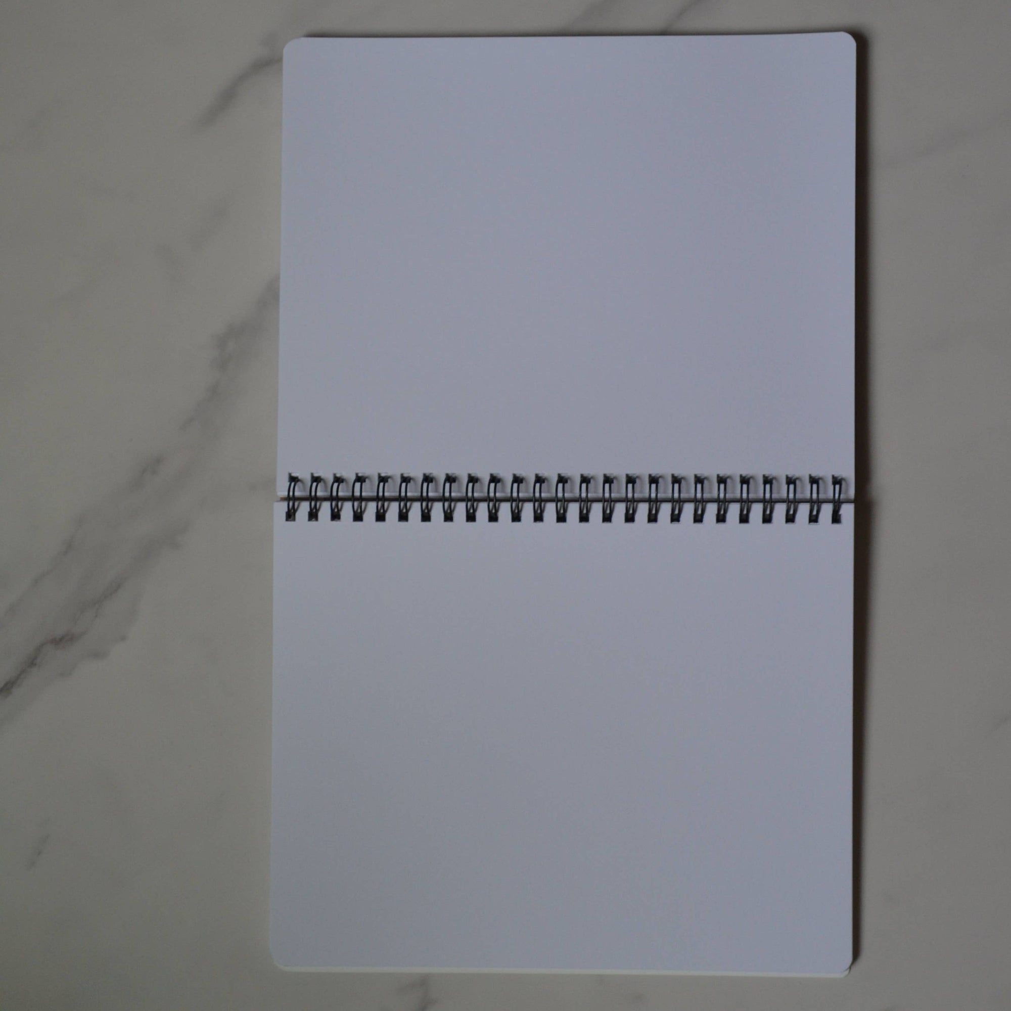 White notebook with a black spiral binding on a marble surface