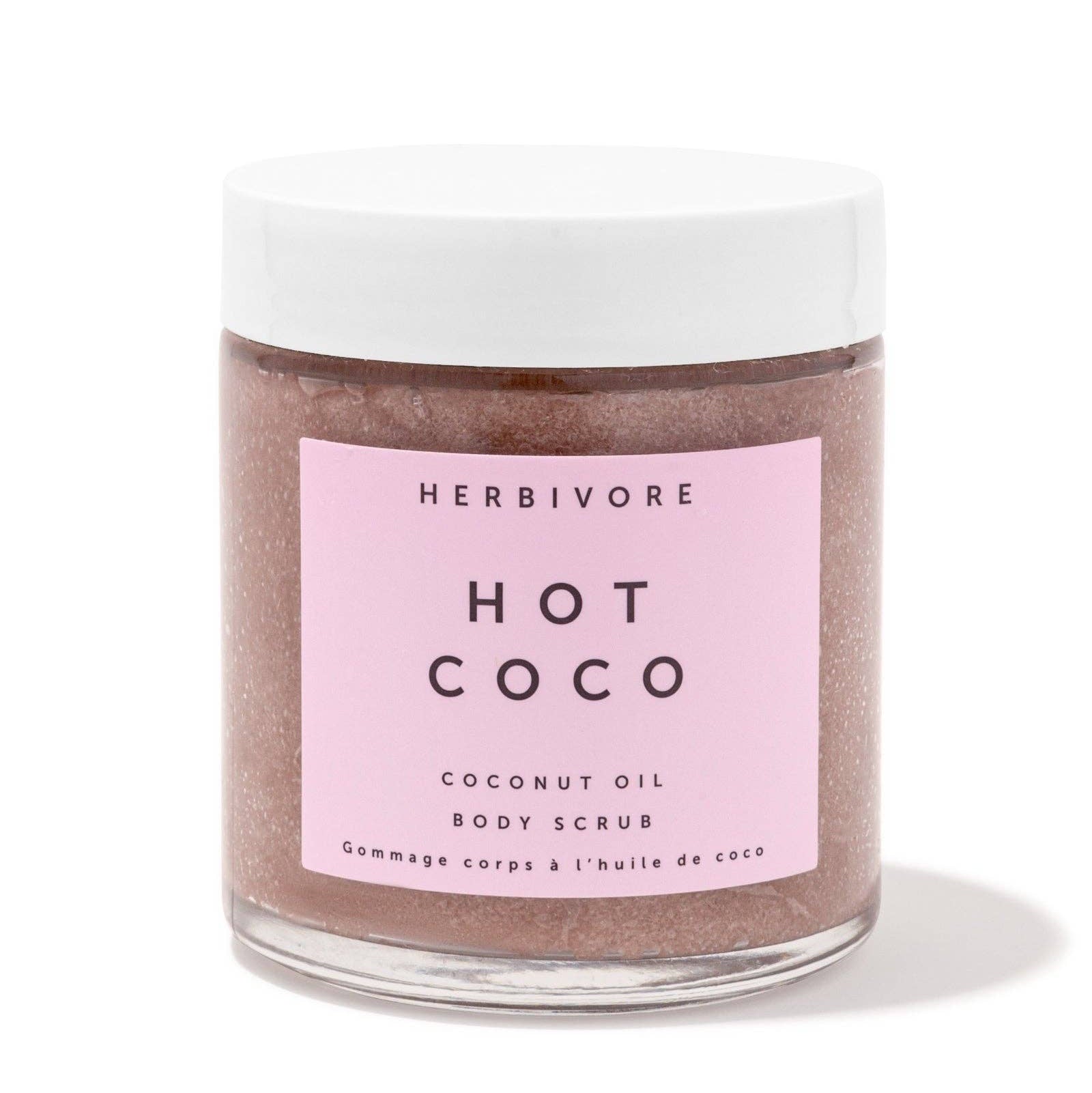 Herbivore Hot Coco coconut oil body scrub in a glass jar with a pink label on a white background