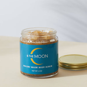 Jar of body scrub with blue label and gold lid on a light background