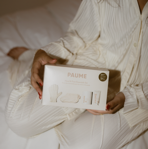 Person holding a box labeled 'PAUME' in a white outfit.