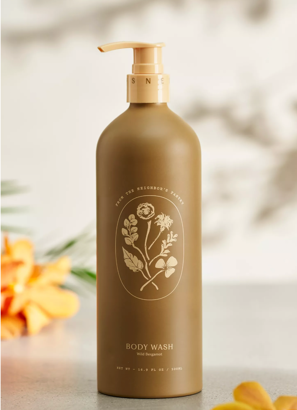 Brown body wash bottle with floral design on a blurred natural background
