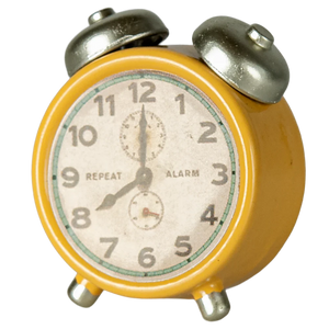 Vintage-style alarm clock with yellow body and silver accents on a white background.