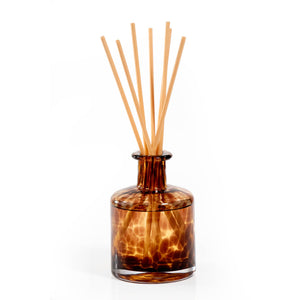 Brown glass diffuser bottle with wooden sticks on a white background