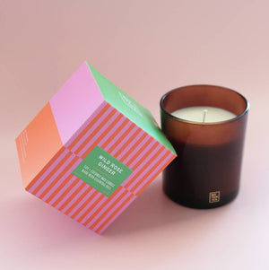 Candle with a colorful box on a light pink background