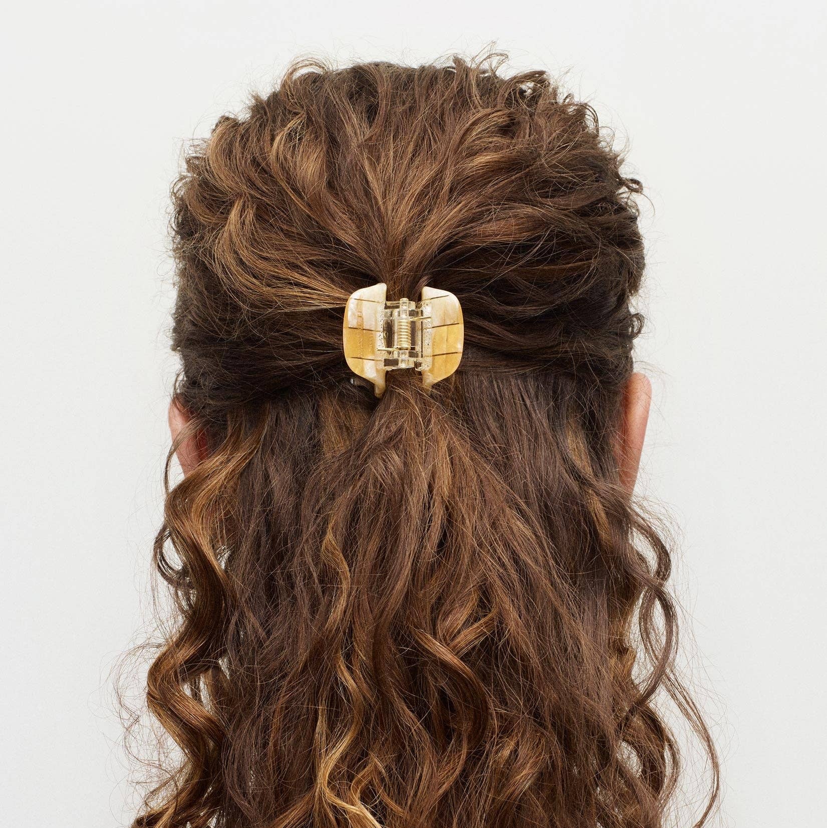 Curly hair with a gold hair clip on a white background