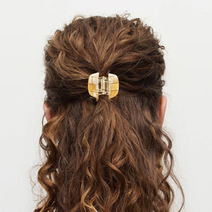 Curly hair with a gold hair clip on a white background