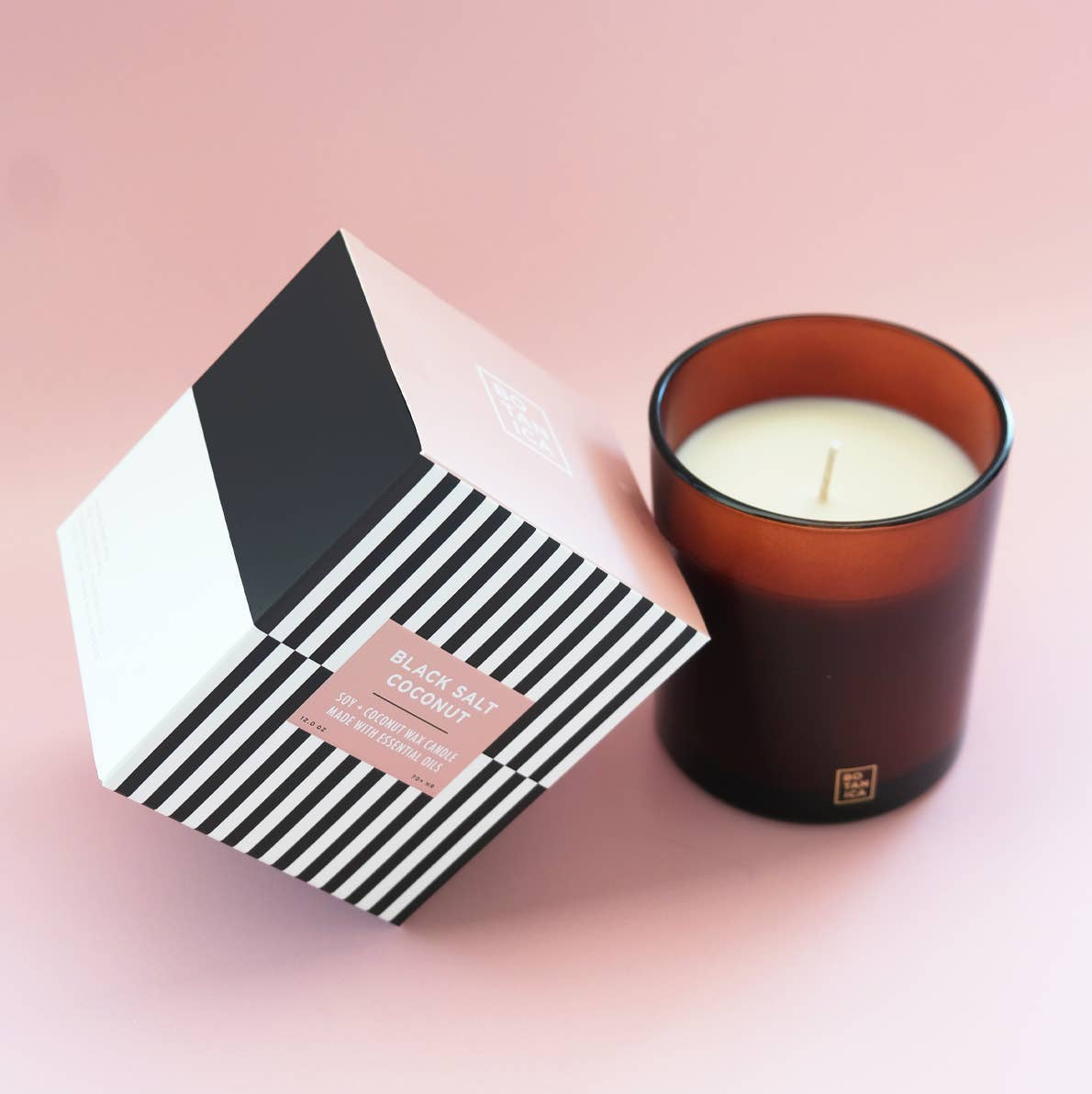Candle and its packaging on a pink background