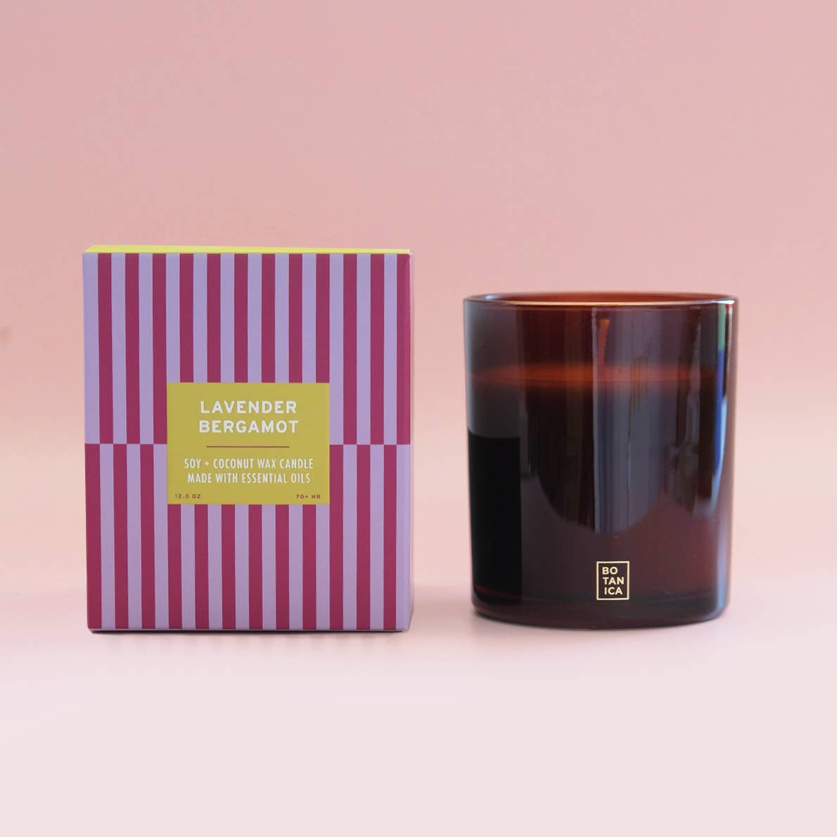 Candle with striped packaging on a pink background