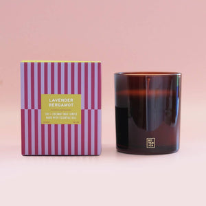 Candle with striped packaging on a pink background