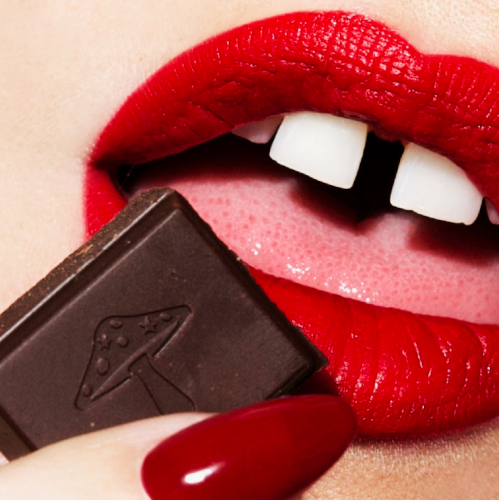 Close-up of a person with red lipstick holding a chocolate bar.