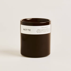 Black candle with a white label on a light beige background