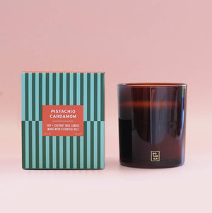 Candle with striped packaging on a pink background