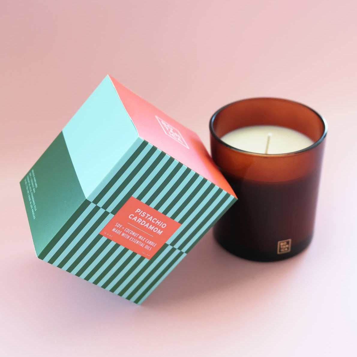 Candle with striped packaging on a pink background