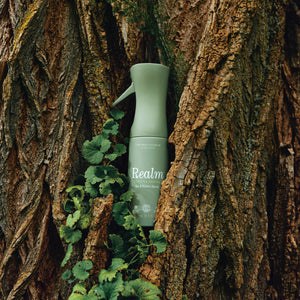 Green bottle labeled 'Realme' against a tree bark background