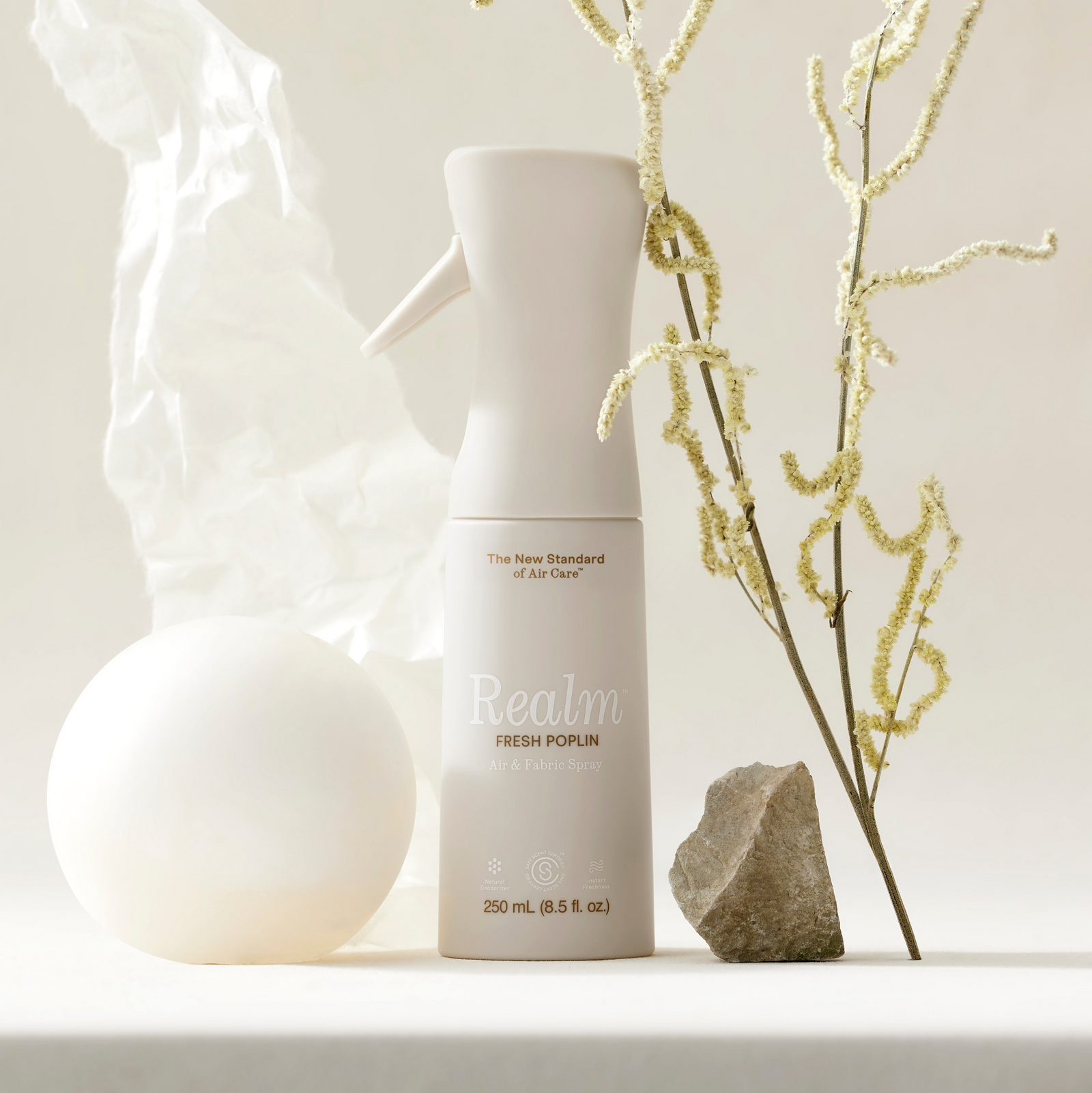 White air freshener bottle labeled 'Realm' on a light beige background