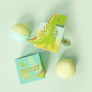 Two small yellow balls with dinosaur-themed packaging on a light green background