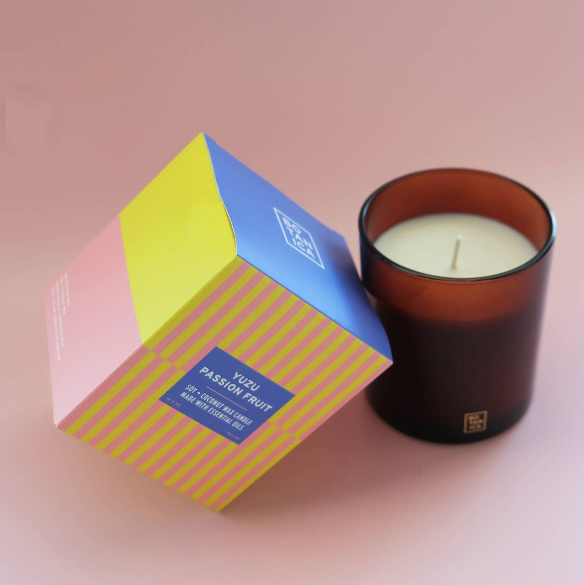 Candle and its packaging with a pink background
