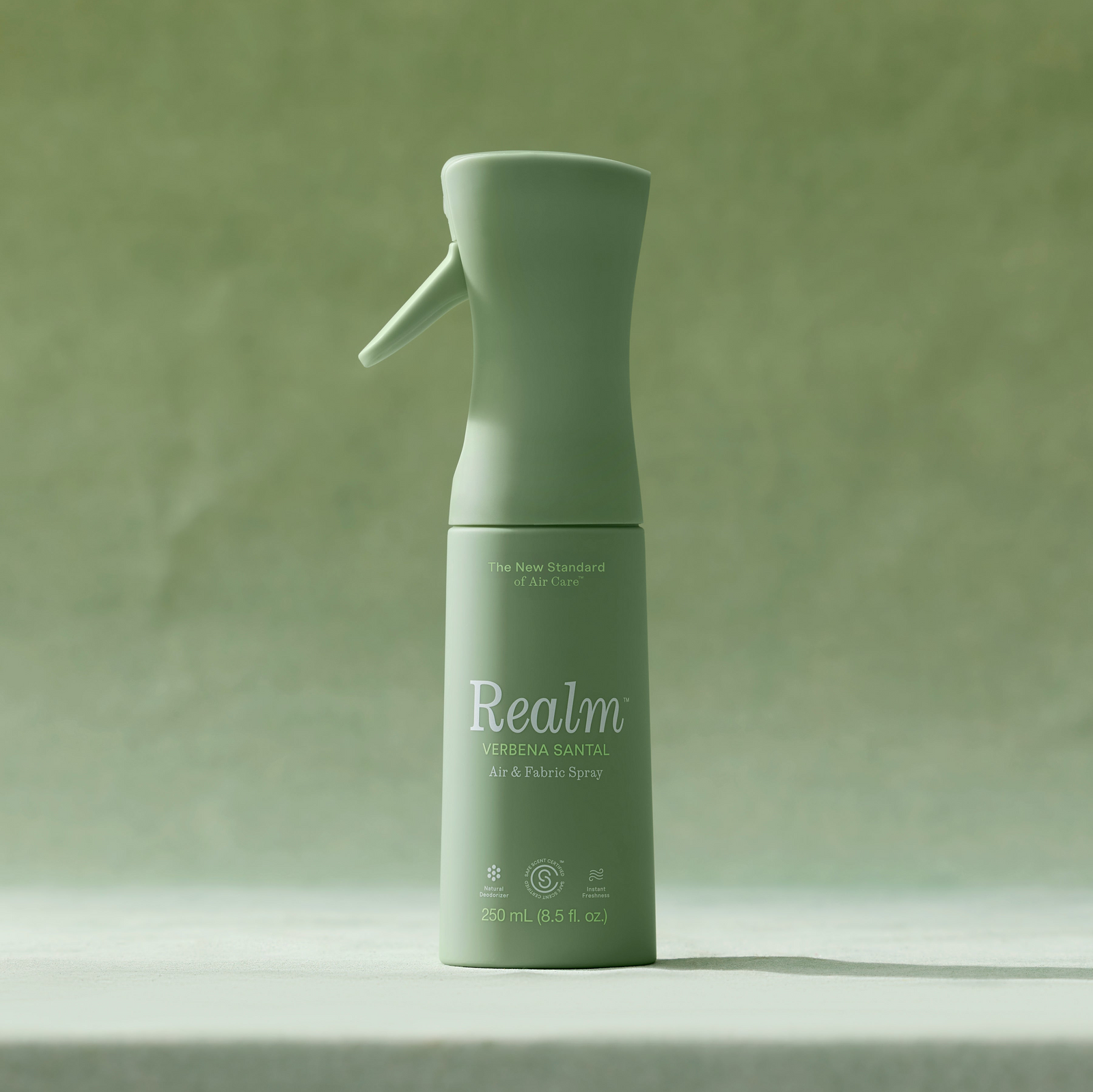 Green spray bottle labeled 'Realm' on a green background