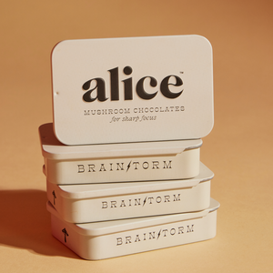 Stack of 'alice' mushroom chocolate tins on a beige background