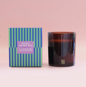 Candle with striped packaging on a pink background