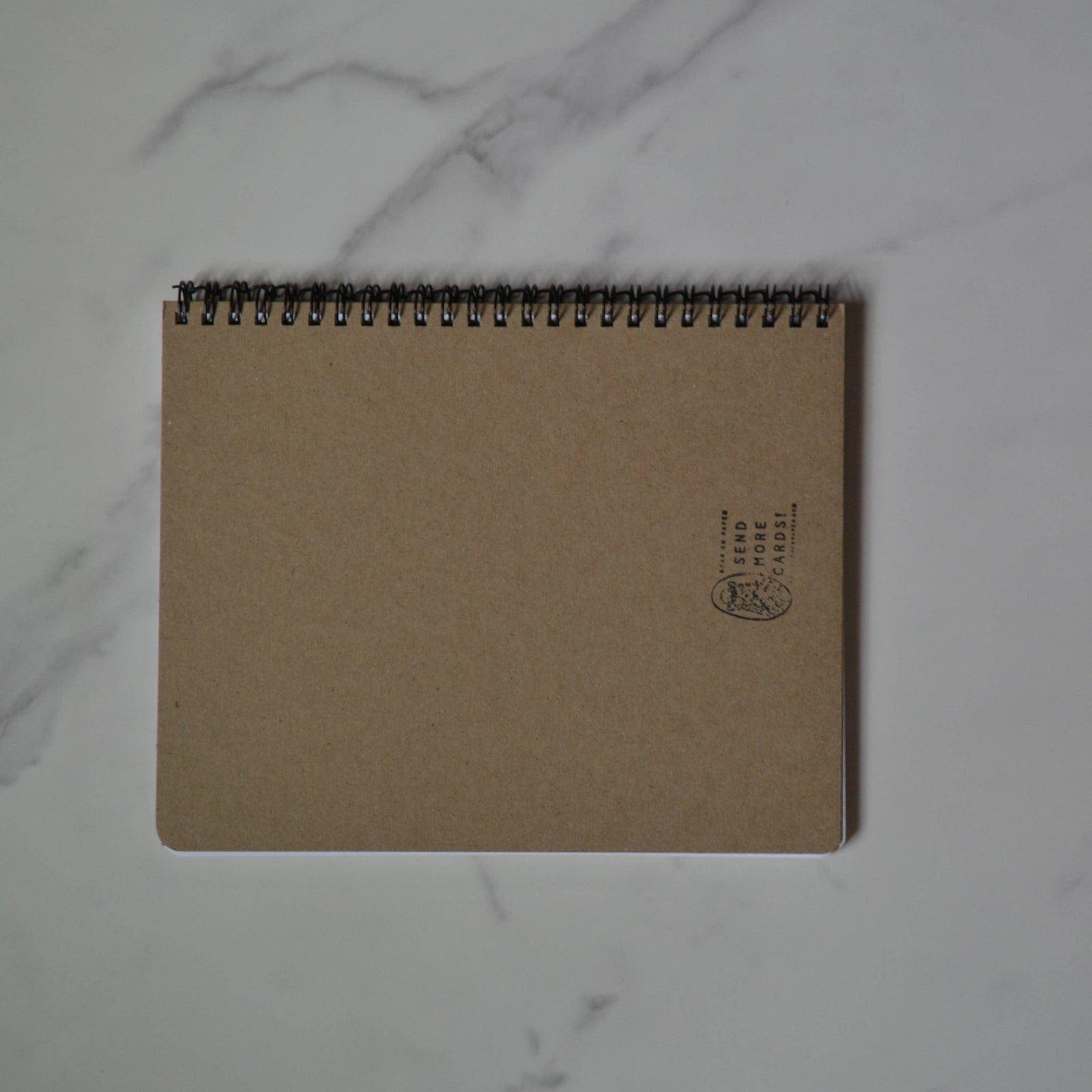 Small notebook with a sardine illustration on a marble surface