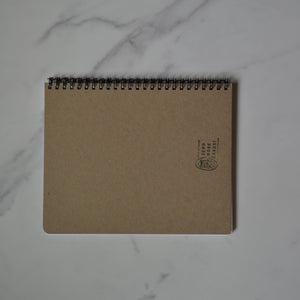Brown notebook with a logo on a marble surface