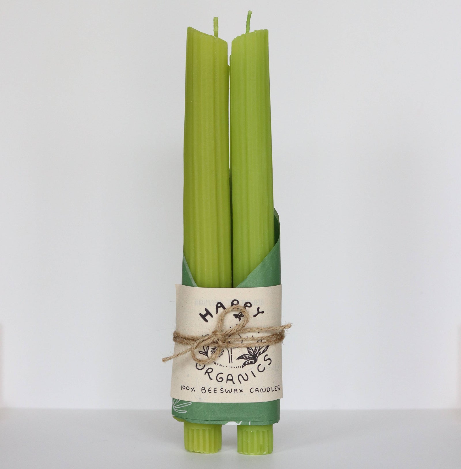 Set of green candles with a 'Happy Organics' label on a white background
