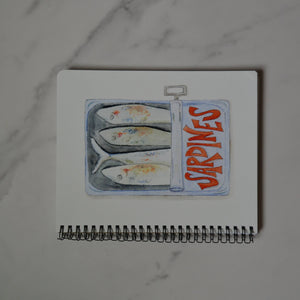 Small notebook with a sardine illustration on a marble surface