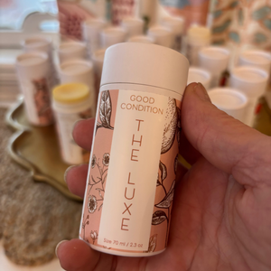 A person holding a tube of The Luxe body moisturizer. 