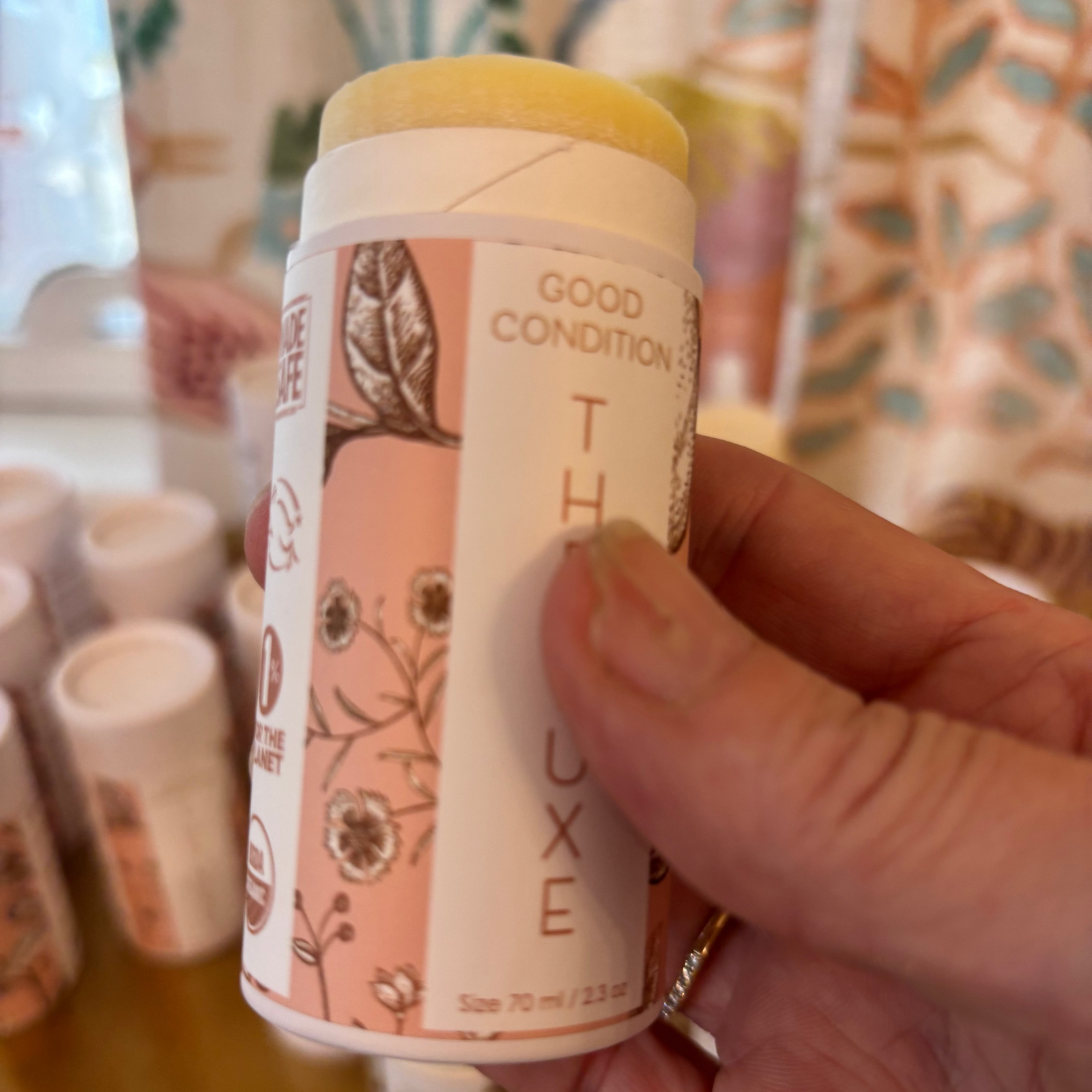 A person holding a tube of The Luxe body moisturizer. 