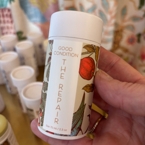 A person holding a tube of The Repair lotion bar. 