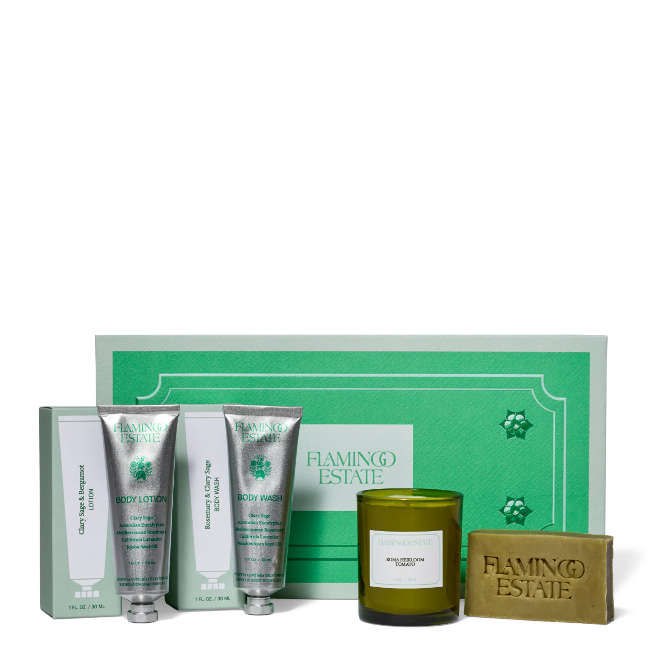 A set of travel-sized bath and home products by Flamingo Estate, including a tomato candle, body lotion, body wash, and soap bar, all displayed in front of a green gift box.