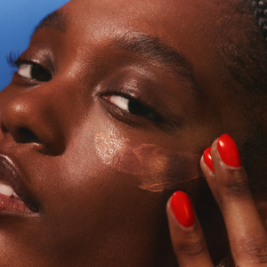 Close-up of a person applying makeup with a brush on a blue background