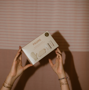 Person holding a 'PAUME' product box against a striped wall.