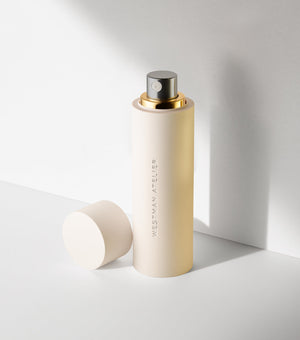 Beige spray bottle with gold cap on a light gray background