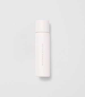 White skincare bottle with brand name on a light gray background