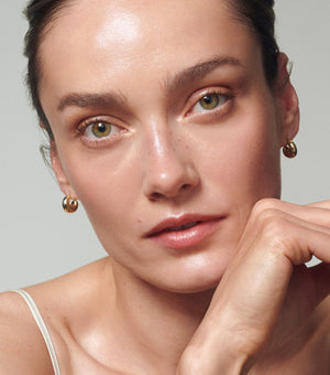 Close-up of a woman with minimal makeup against a neutral background