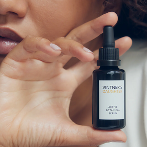 A woman holding a bottle of Vintner's Daughter Active Botanical Serum. 