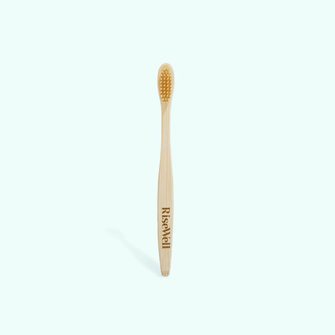 Bamboo toothbrush with 'RiseWell' branding on a white background