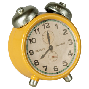 Vintage-style yellow alarm clock with a white face on a white background