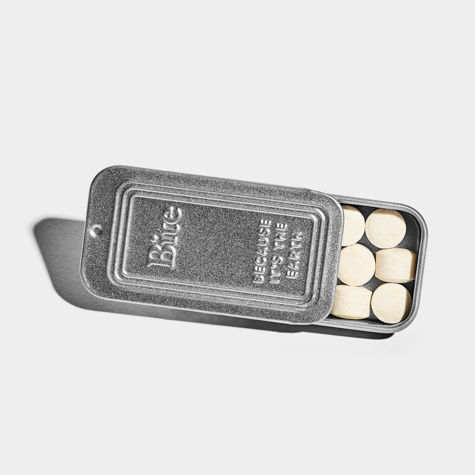 An open aluminum travel tin with toothpaste bits visible inside.