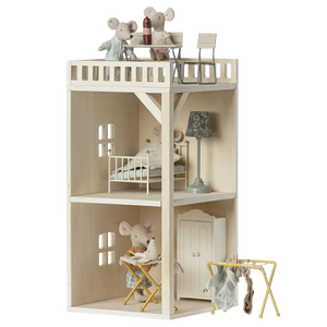 A toy mouse hole farmhouse annex with multiple floors, furniture, and a terrace, made of beige wood.