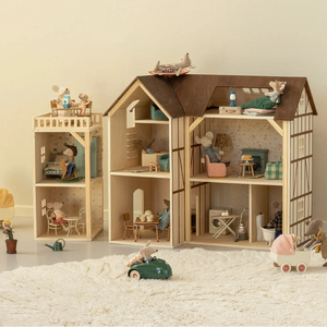 Wooden dollhouse with miniature furniture and toys on a light surface.