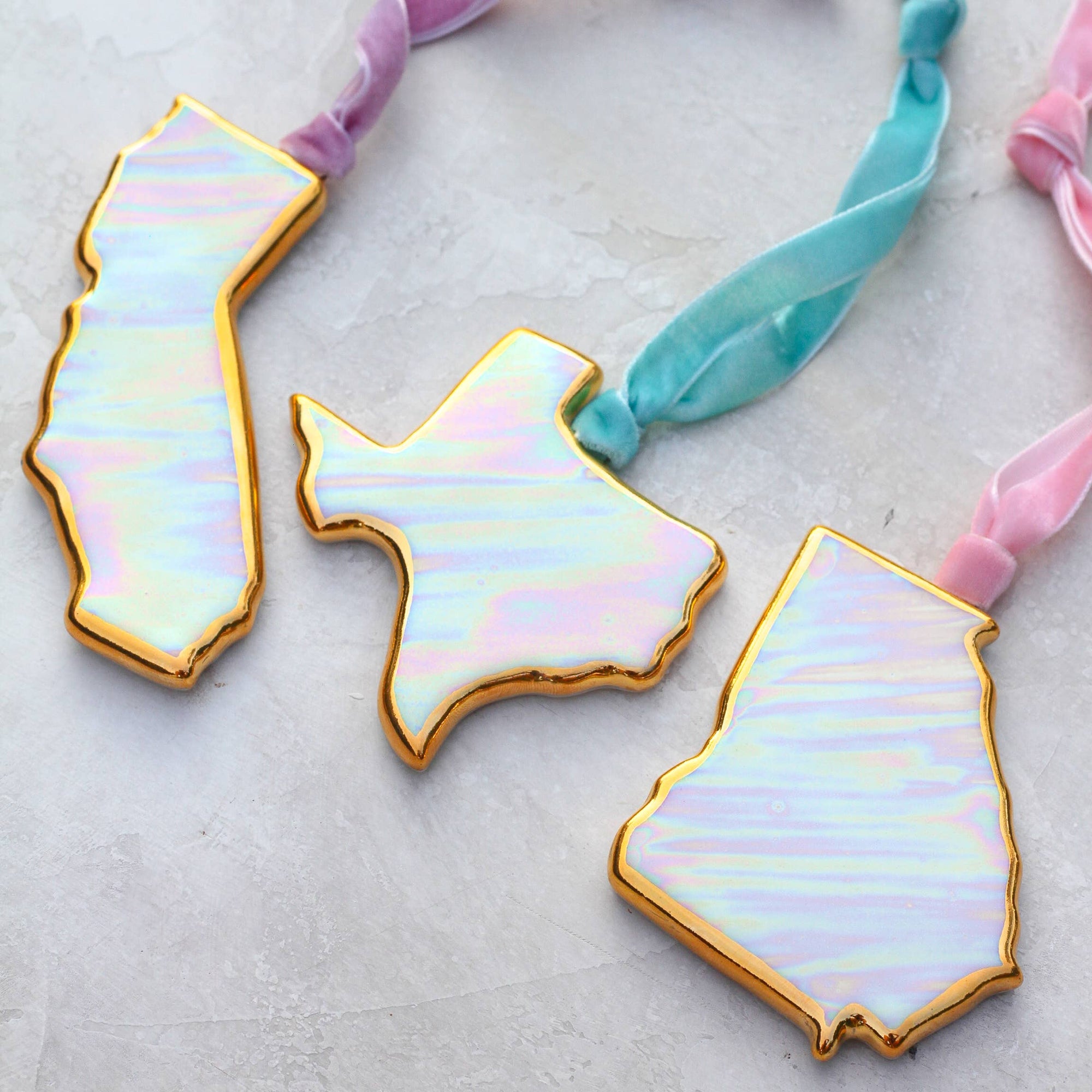 Iridescent state-shaped hair ties on a light background
