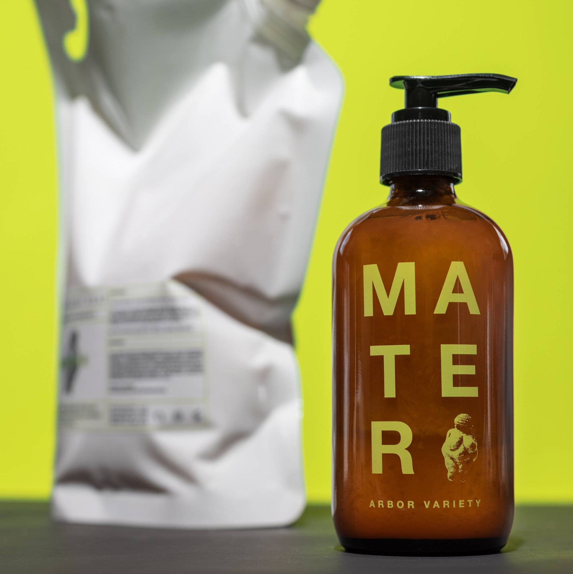 A bottle of mater arbor soap with a refill bag in the background. 