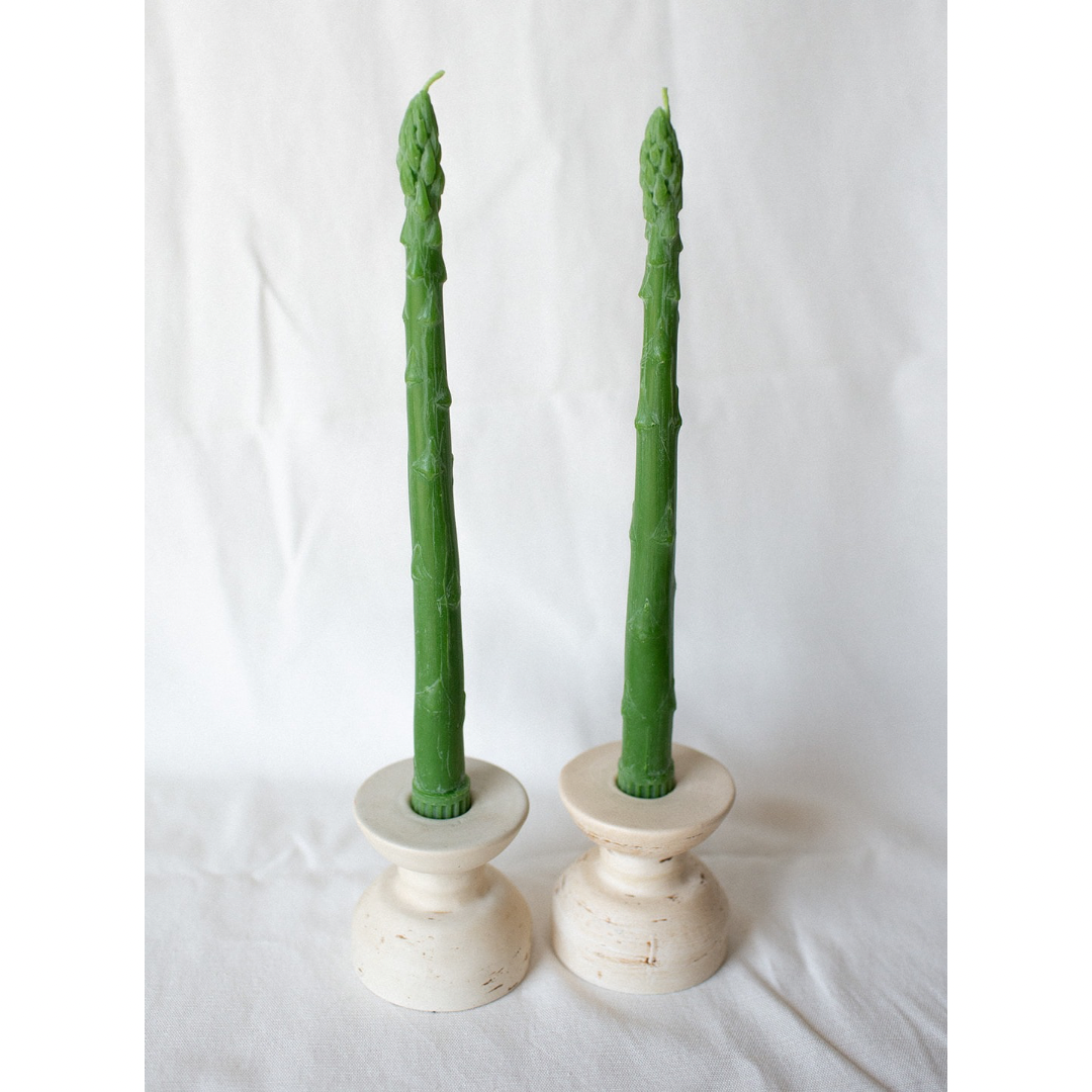 A set of taper candles shaped like asparagus spears, in white candle holders