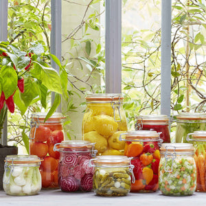 Assorted le parfait glass containers holding canned fruits and vegetables. 