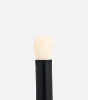 Makeup brush with black handle and white bristles on a light gray background